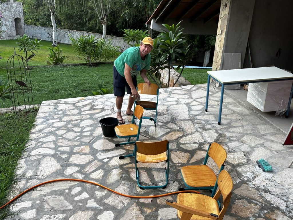 Ein Mann reinigt Stühle vor einem Haus im Freien