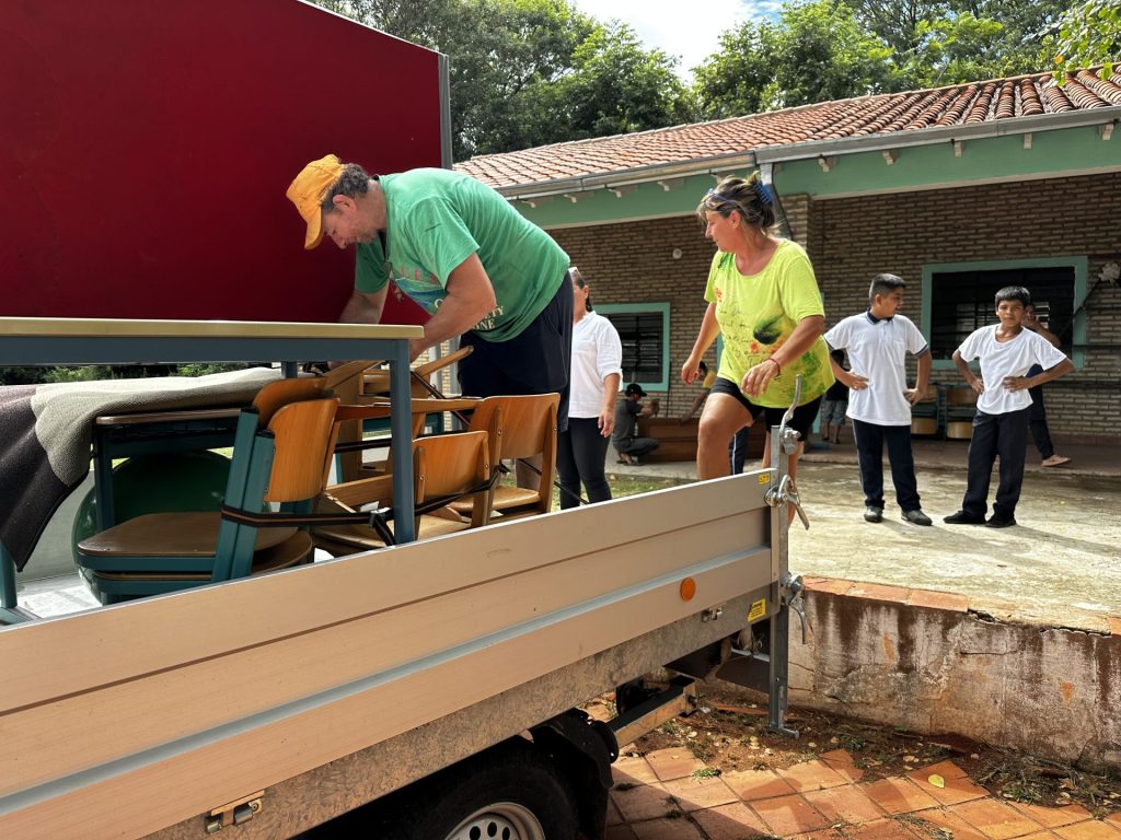 Ein Mann putzt Stühle draußen vor einem Wohnhaus.